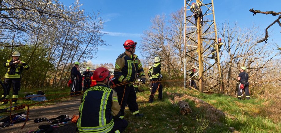Feuerwehrangehörigen üben am Hochspannungsmast