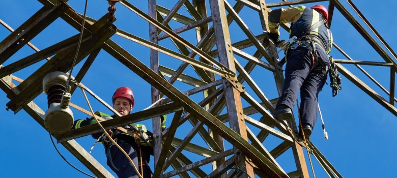 Zwei Feuerwehrangehörige, gesichert auf dem Strommast