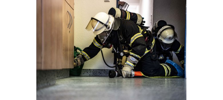 2 Feuerwehrangehörige kniend auf Boden bei Personensuche unter Nullsicht