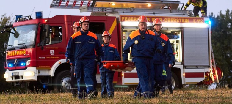 Jugendliche tragen eine Person (Dummy) in der Schleifkorbtrage