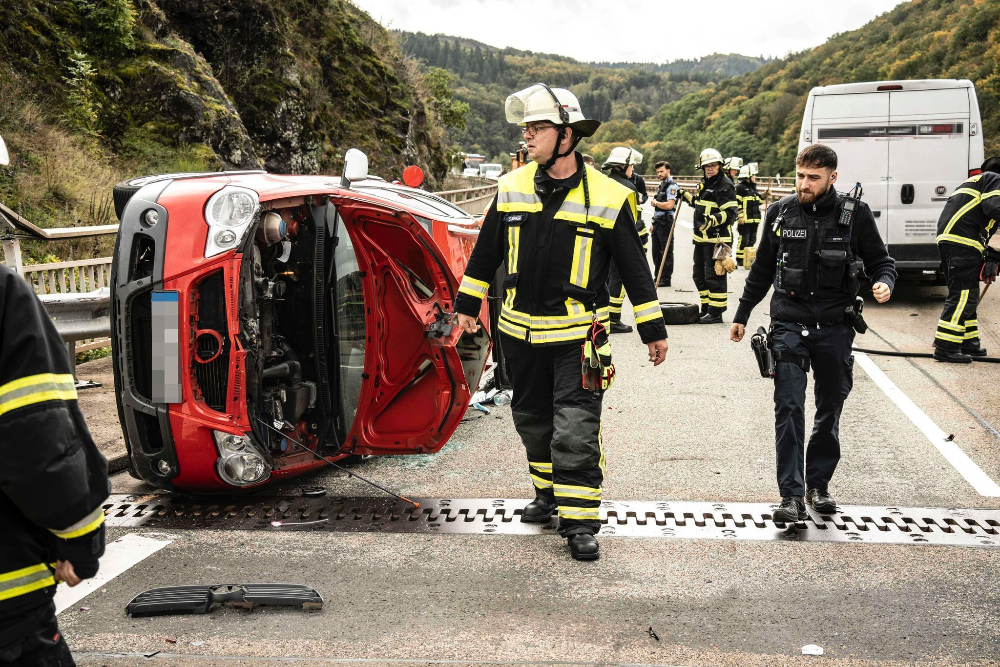 Verunfallter Pkw auf der Seite liegend und Einsatzkräfte