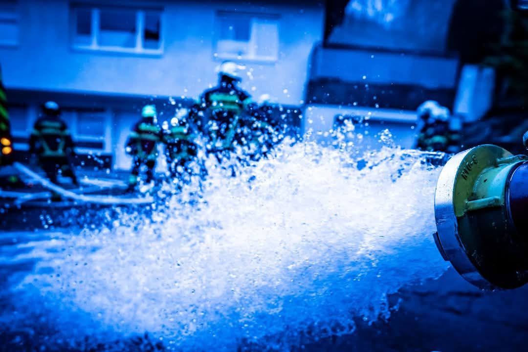 Löschschlauch aus dem Wasser spritzt vor dem Haus der brennenden Sauna