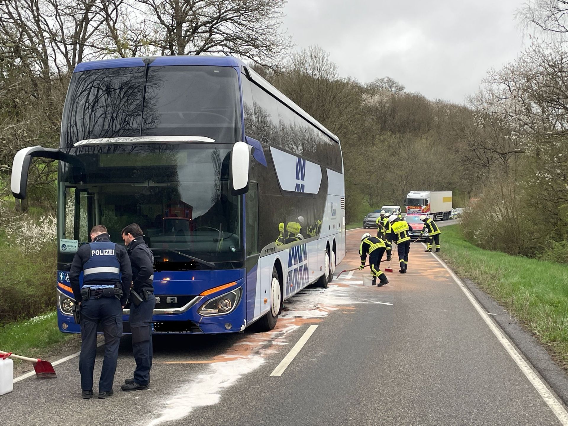 Bus mit abgestreuten, auslaufendem Öl und Einsatzkräften