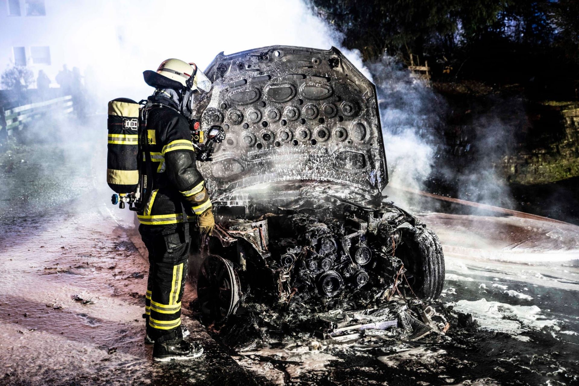 Feuerwehrmann steht vor verbranntem Pkw