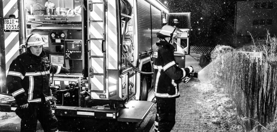 Feuerwehrmann beim Löschen der Hecke