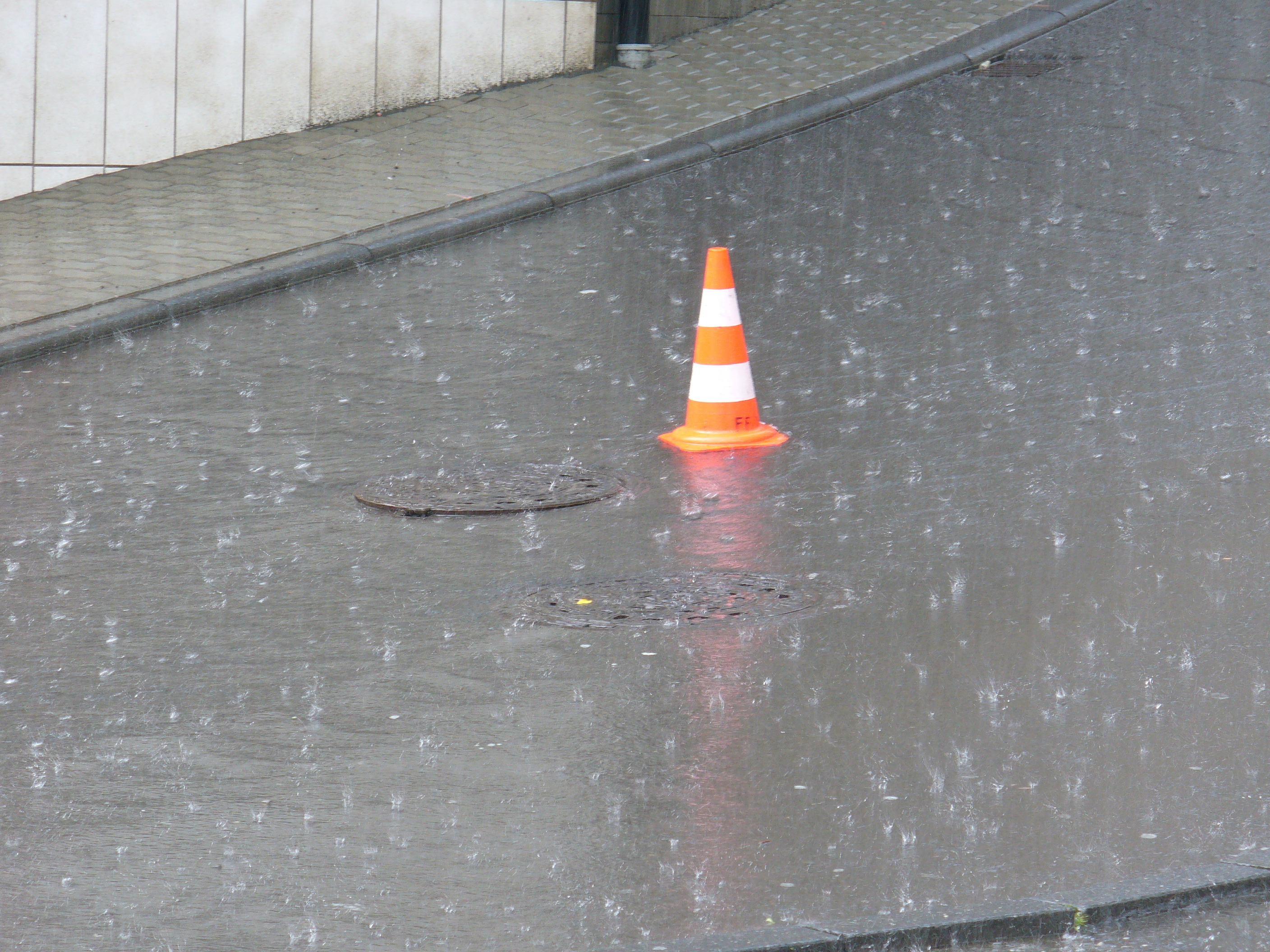 Verregnete Straße mit Leitkegel